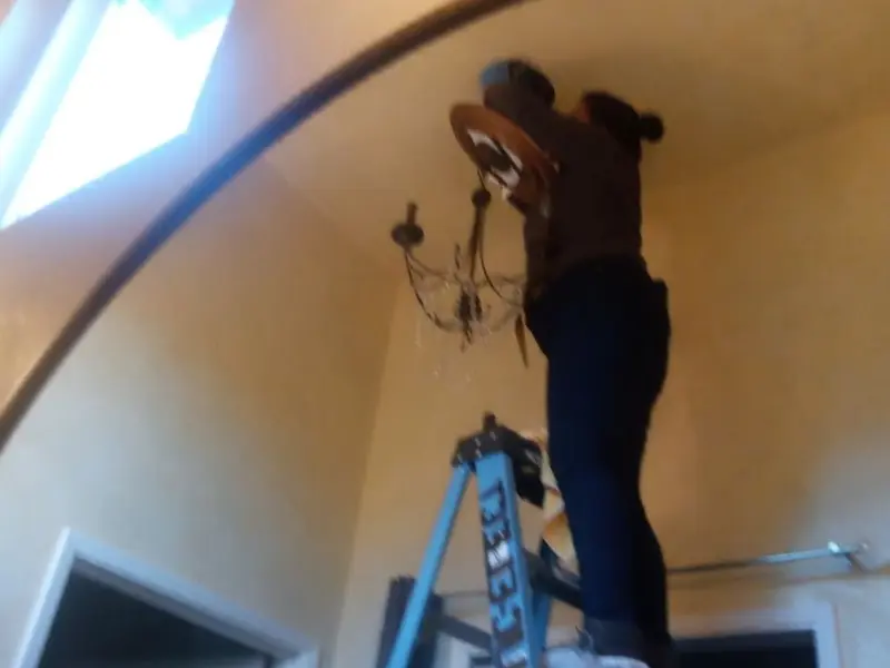 Electrician installing a chandelier in a Nash residence